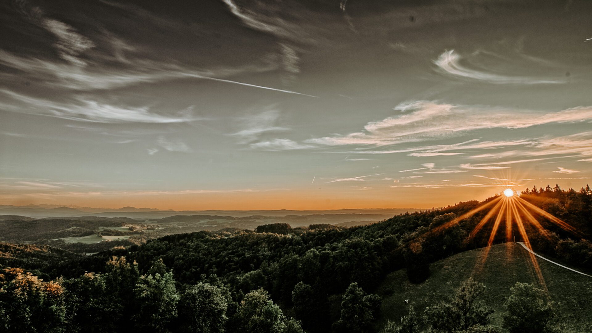 Dramatic sunset over a rolling landscape with mountains